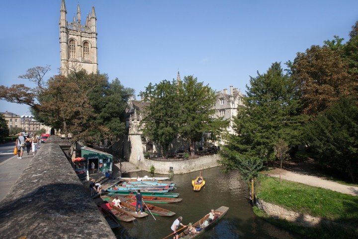 punts on a canal with a stone building in the background