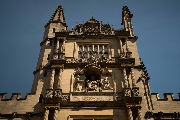 Ornate stone building façade with statues and columns under a clear blue sky.