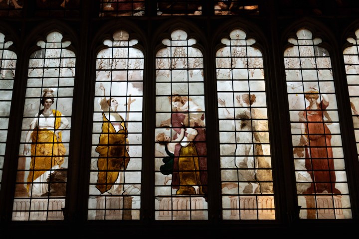 Stained glass windows depicting figures in classical attire, five panels with intricate details.