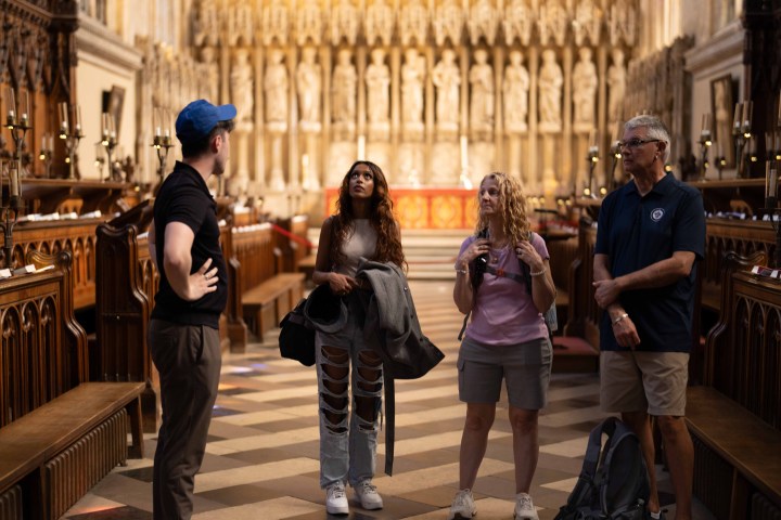 Four people standing inside a historic cathedral with ornate wooden carvings.