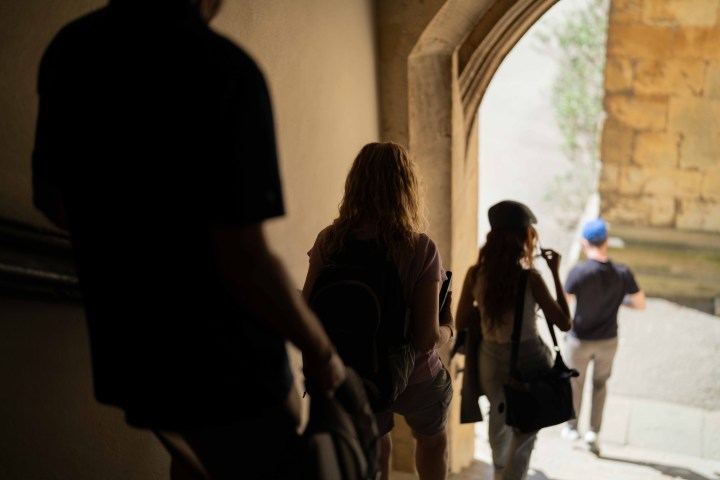 People descending a dimly lit staircase towards an archway opening.