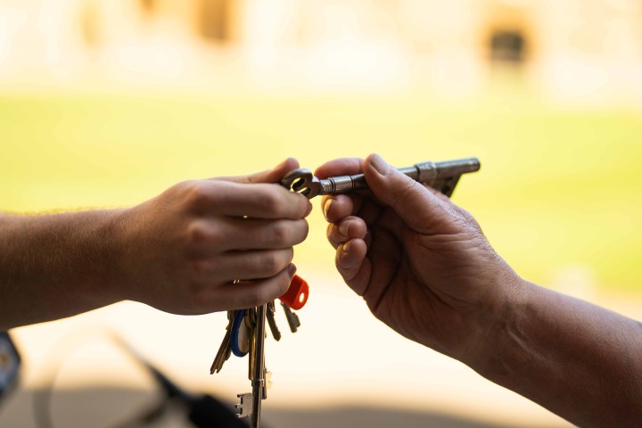 Two hands exchanging keys with a blurred background.