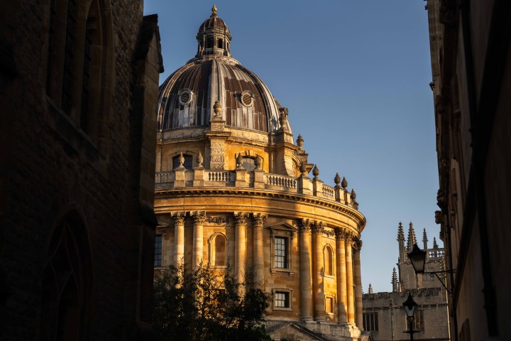 Historic domed building with blue sky in the background, partially framed by shadowed walls.